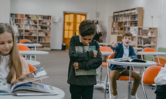 A boy being bullied by classmates in a school classroom setting.